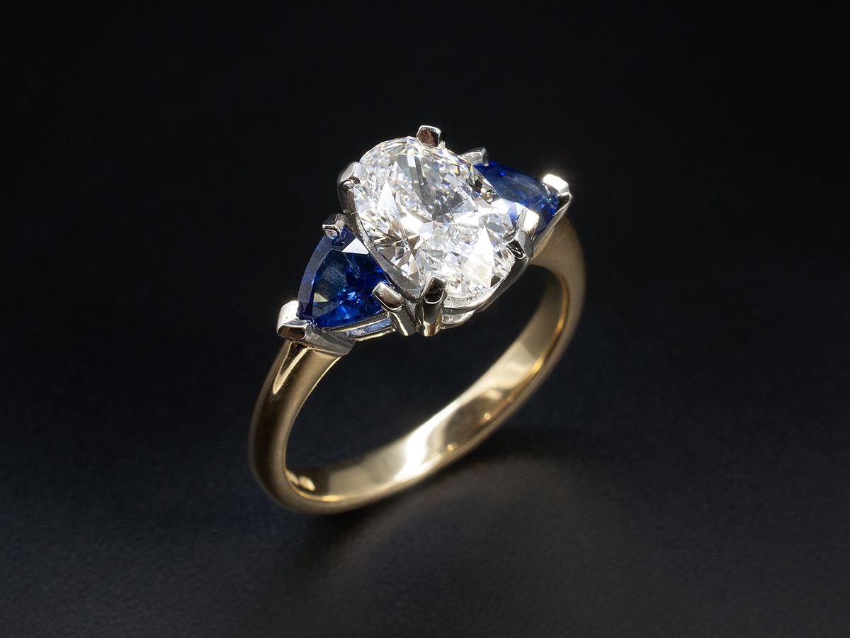 Oval diamond and trillion sapphires, in yellow gold and platinum.